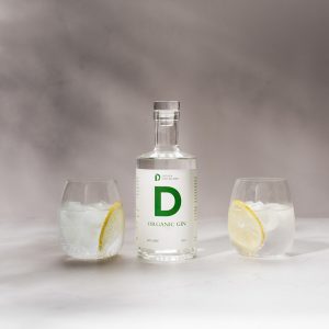 Picture of a bottle of organic gin and two glasses containing lemon ice and clear liquid